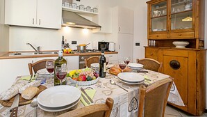 A dining area with a table set for a meal, including plates, cutlery, and a bottle of wine. - Riva Centro Apartment (Riva del Garda)