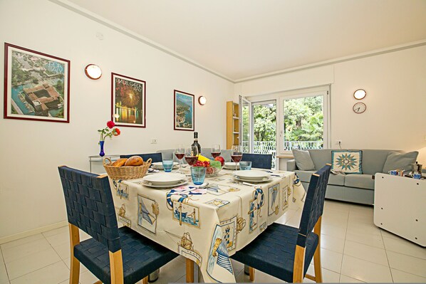 A dining area with a table set for four, chairs, a basket of bread, and a vase with flowers. - Riva Lago e Spiaggia Apartment 3 (Riva del Garda)