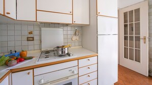 A kitchen with white cabinets, a stove, and a refrigerator. - Easy Central Stresa in Stresa (Stresa)