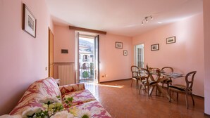 A living room with a sofa and a dining area with a table and chairs. - Easy Central Stresa in Stresa (Stresa)