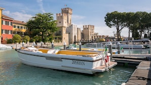 Een boot afgemeerd in een jachthaven, met een kasteel op de achtergrond.