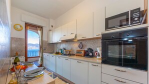Een moderne keuken met witte kastjes, een magnetron, een oven en een raam met uitzicht.