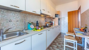 Een moderne keuken met witte kasten, een roestvrijstalen spoelbak en een houten eettafel gedekt met borden en glazen.