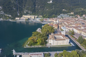 An aerial view of a coastal town with a marina, historic buildings, and a prominent castle on a hill. - Casa Alpino 5 in Riva del Garda (Riva del Garda)