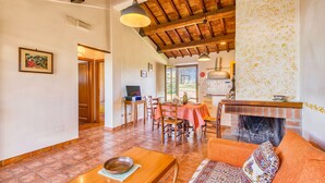 A spacious living area with a fireplace, dining table, and comfortable seating. - Myrtle apt With Shared Pool (Castiglione del Lago)