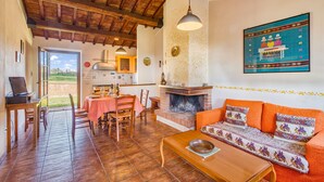 A cozy living room with a fireplace, wooden furniture, and a dining area with a table and chairs. - Myrtle apt With Shared Pool (Castiglione del Lago)