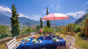 Tavolo apparecchiato all'aperto con vista su montagne e una città sullo sfondo.