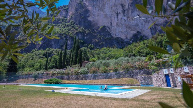 Una piscina con un edificio in pietra e montagne sullo sfondo.