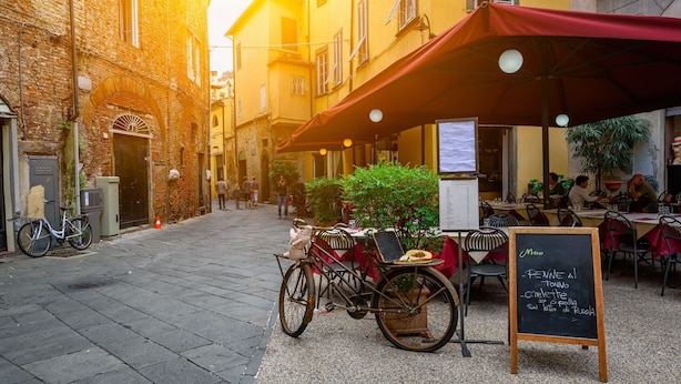 A narrow street with a café, bicycles, and outdoor seating. - Claz House in Riva del Garda (Riva del Garda)