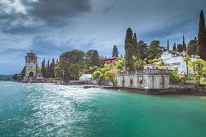 A coastal view with a tower, a red house, and a white building with a balcony. - Claz House in Riva del Garda (Riva del Garda)