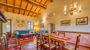 A dining area with wooden furniture, a chandelier, and artwork on the walls. - Sunflower apt With Shared Pool Family fun (Castiglione del Lago)