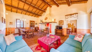 A spacious living room with a high wooden ceiling, a dining area with wooden furniture, and a kitchen area. - Sunflower apt With Shared Pool Family fun (Castiglione del Lago)
