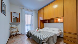 A bedroom with a bed, wooden wardrobe, a radiator, a small wooden chair, and a window with curtains. - Casa Dolce Casa Stresa (Stresa)