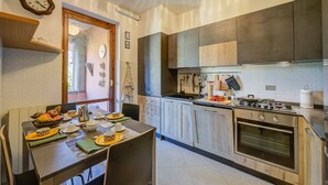 Een moderne keuken met houten kastjes, een gasfornuis en een eethoek met borden en kommen.