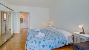 A bedroom with a bed, bedside tables, a mirror, and a radiator. - Il Piccolo Nido in Riva del Garda (Riva del Garda)