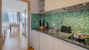 A modern kitchen with a green-tiled backsplash, a stainless steel sink, and a black toaster. - Il Piccolo Nido in Riva del Garda (Riva del Garda)