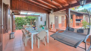 A covered patio with a dining table, chairs, and a reclining chair. - Villa Oasi With Private Pool (Sirmione)