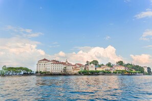 A waterfront hotel with multiple buildings, a large body of water in the foreground, and a clear sky. - Laura s Cozy Apartment Stresa Center (Stresa)