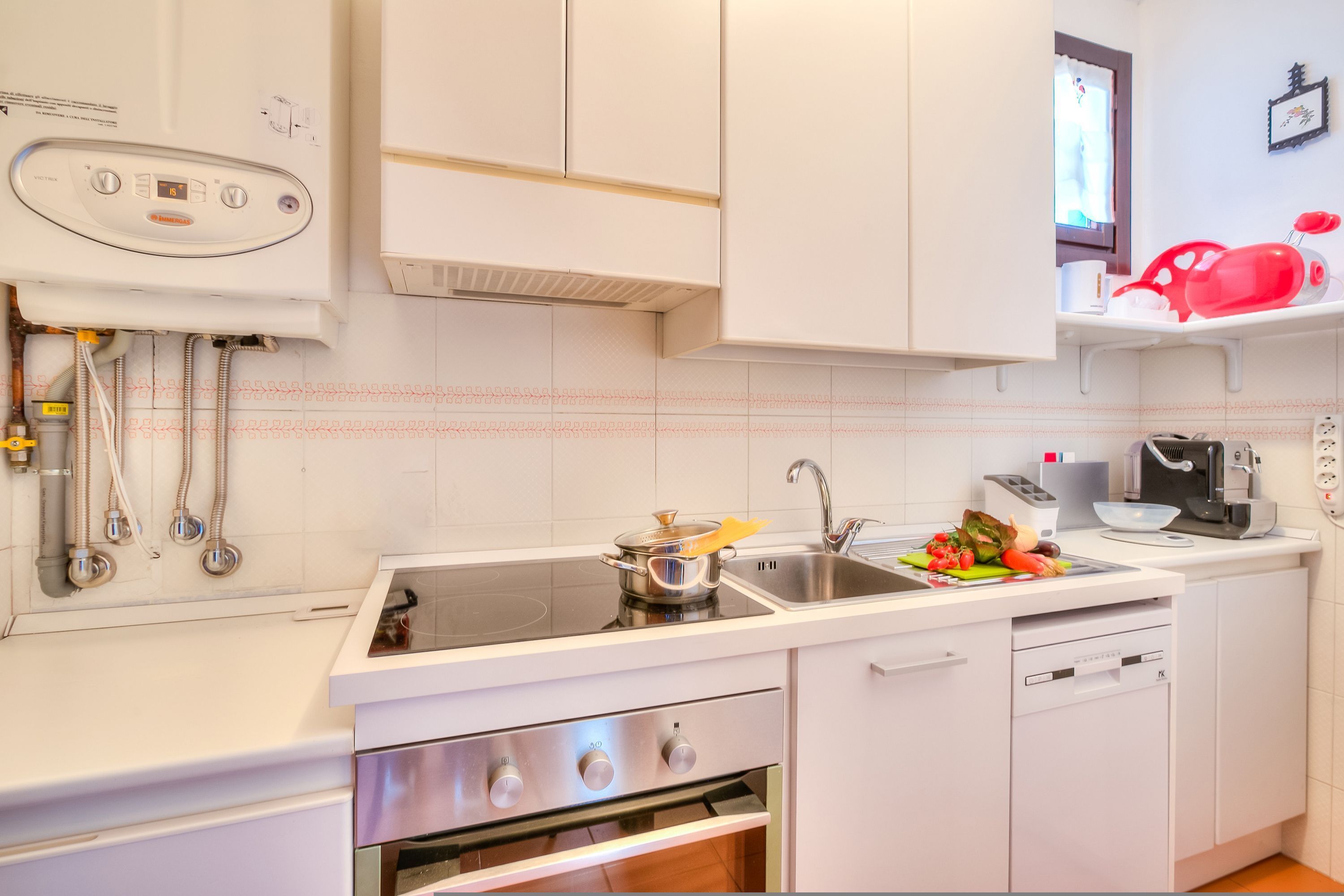 A modern kitchen with white cabinets, a built-in oven, a sink, and a dishwasher.
