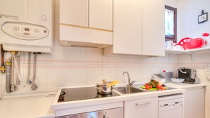 A modern kitchen with white cabinets, a built-in oven, a sink, and a dishwasher.