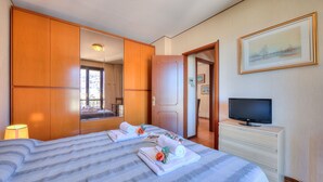 A hotel room with a large bed, a television, a dresser, and a mirror.