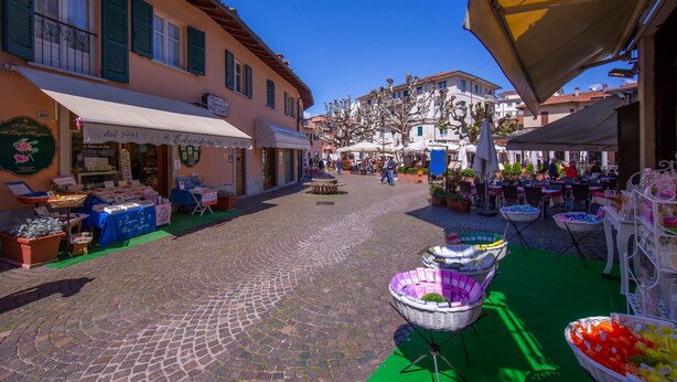Une rue pavée bordée d’étals de marché en plein air, d’une boutique de fleurs et d’un restaurant.