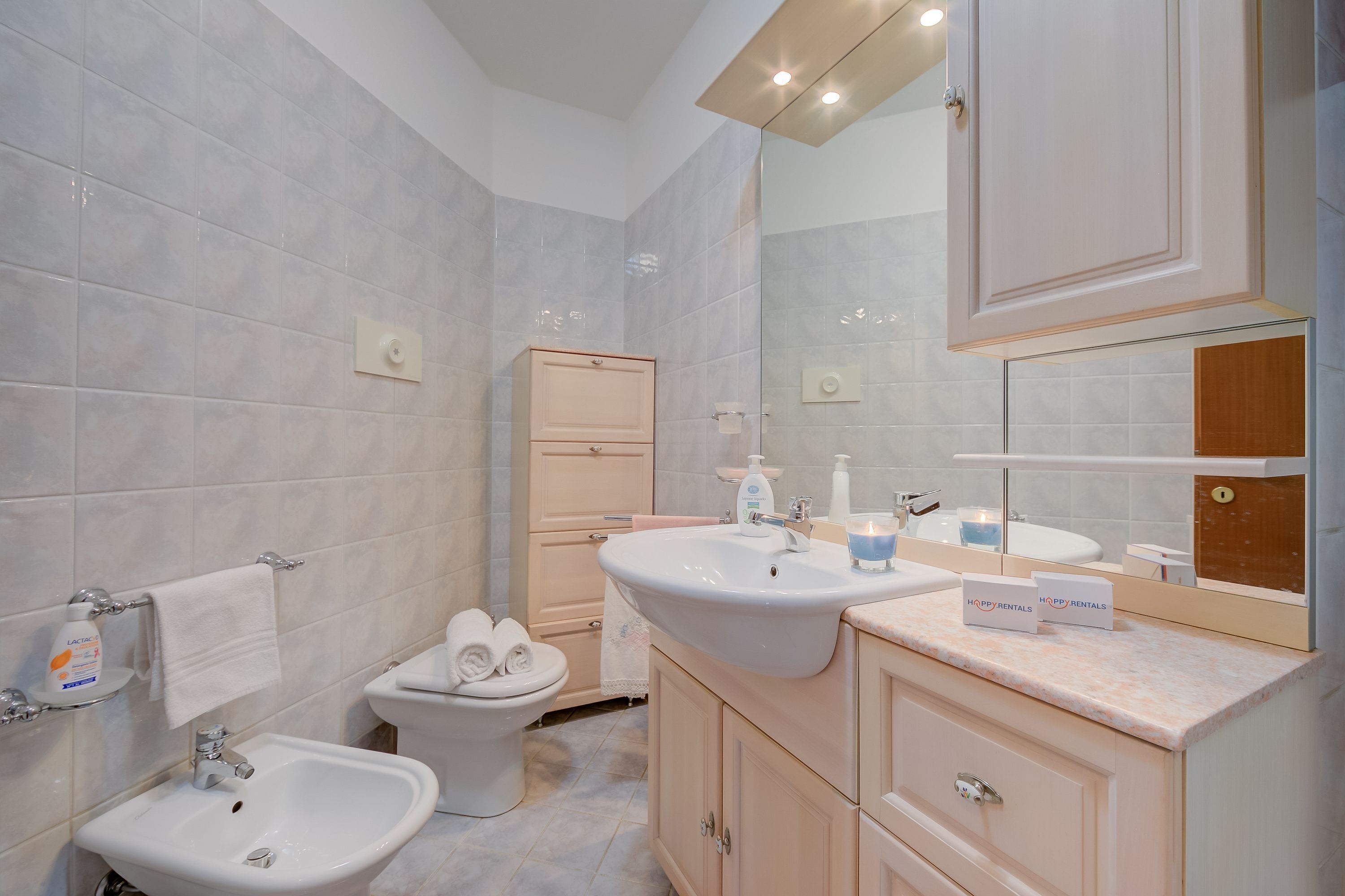 A modern bathroom with a bidet, a toilet, a sink, and a mirror.