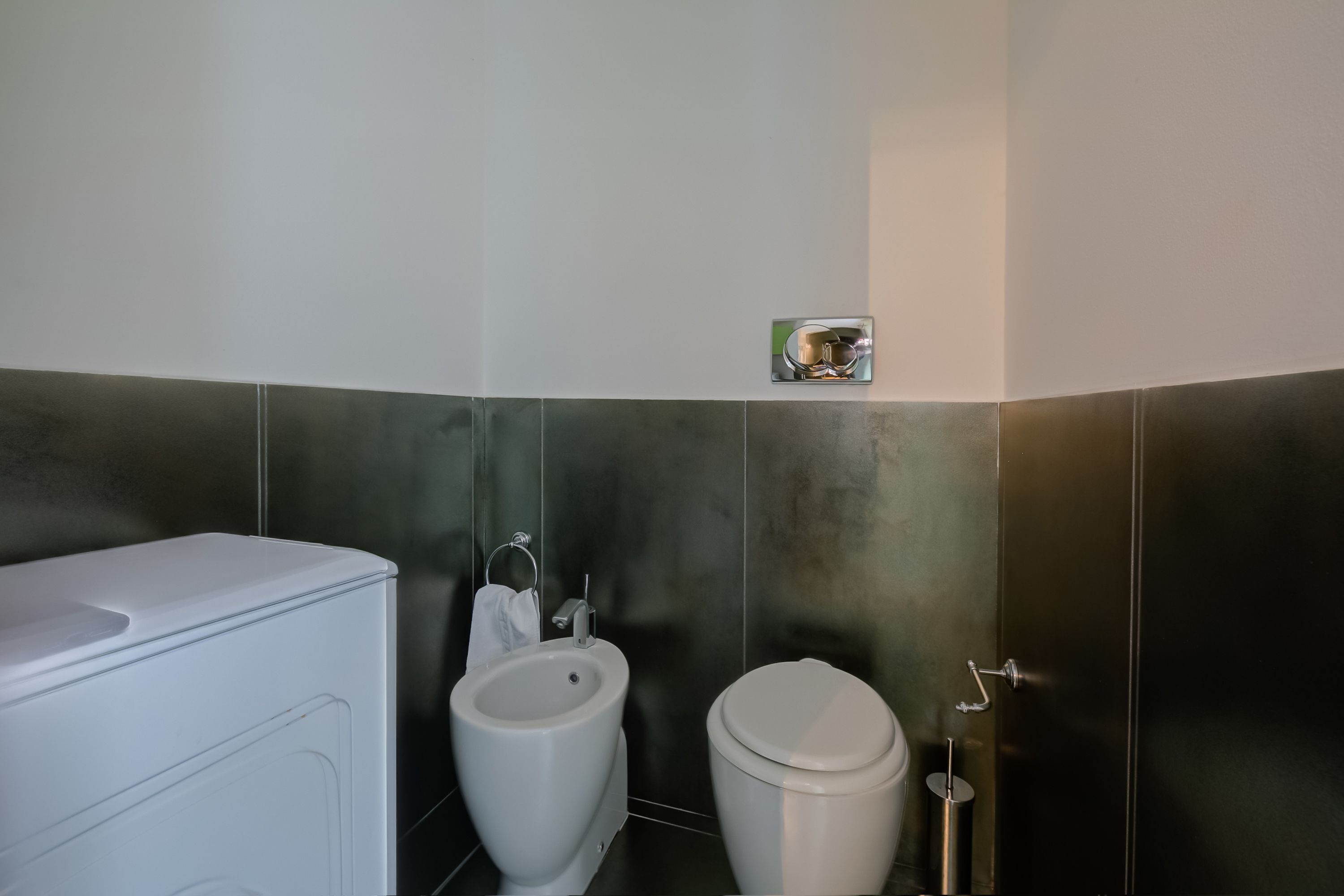 A modern bathroom with a toilet, bidet, and a white washing machine.