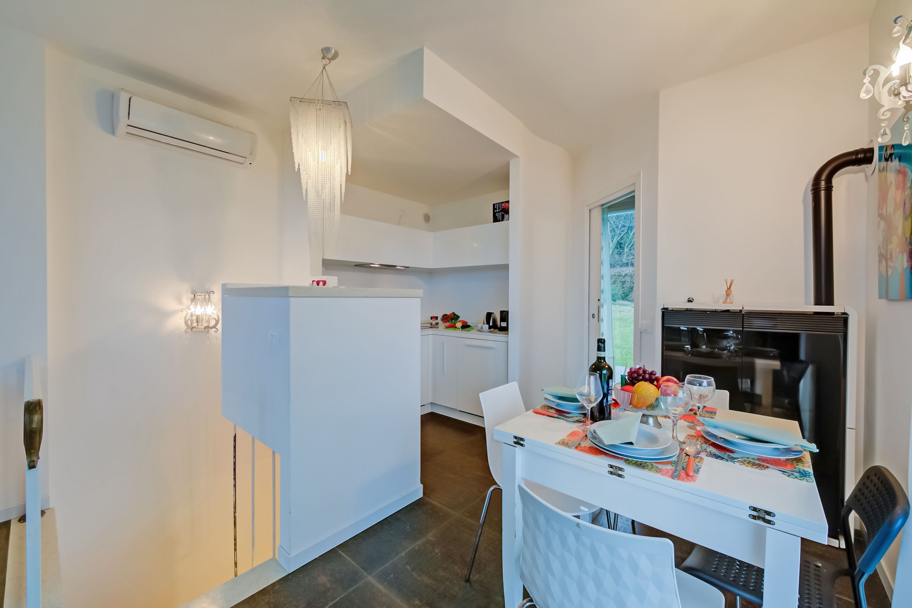 A modern kitchen with white cabinetry, a dining table set with plates, glasses, and a fruit bowl.