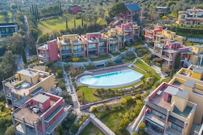 Un moderno complejo residencial con varios edificios, una piscina central y zonas verdes circundantes.