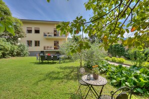 A residential building with a balcony, a lawn, and a garden with potted plants. - The Bon Ora Apartment (Riva del Garda)