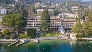 Ein Hotel am Seeufer mit mehreren Gebäuden, einem Steg und freiem Blick auf die umliegenden Hügel.