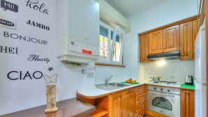 Une cuisine compacte avec des meubles en bois, un four encastré et une fenêtre au-dessus de l’évier.