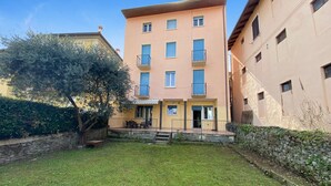 Un immeuble à plusieurs étages doté de balcons, d’un mur en pierre et d’une cour verdoyante.