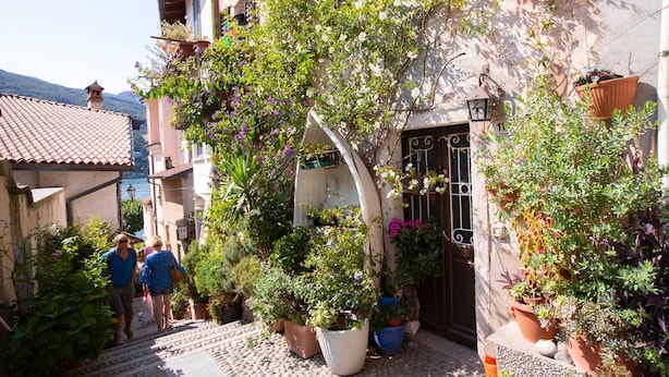 A narrow street with steps leading to a building with a tiled roof and potted plants. - Riccardo House Stresa (Stresa)