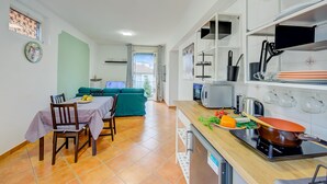 A modern kitchen with a dining area, a green sofa, and a view to the outside. - Riccardo House Stresa (Stresa)