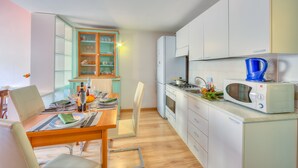 Een kleine keuken met een eethoek, met een magnetron, een spoelbak en een raam met gezandstraald glas.