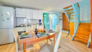 Een moderne keuken met witte kasten, een eettafel gedekt met borden, glazen en een fles. Een magnetron en fornuis zijn zichtbaar.