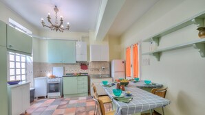 A kitchen with a dining table, chairs, a stove, and a refrigerator. - Il Porticciolo Stresa (Stresa)