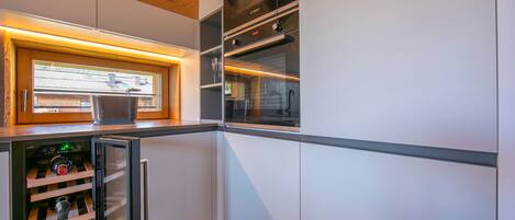Una cocina moderna con electrodomésticos integrados, un refrigerador de vinos y un ventanal que proporciona luz natural.
