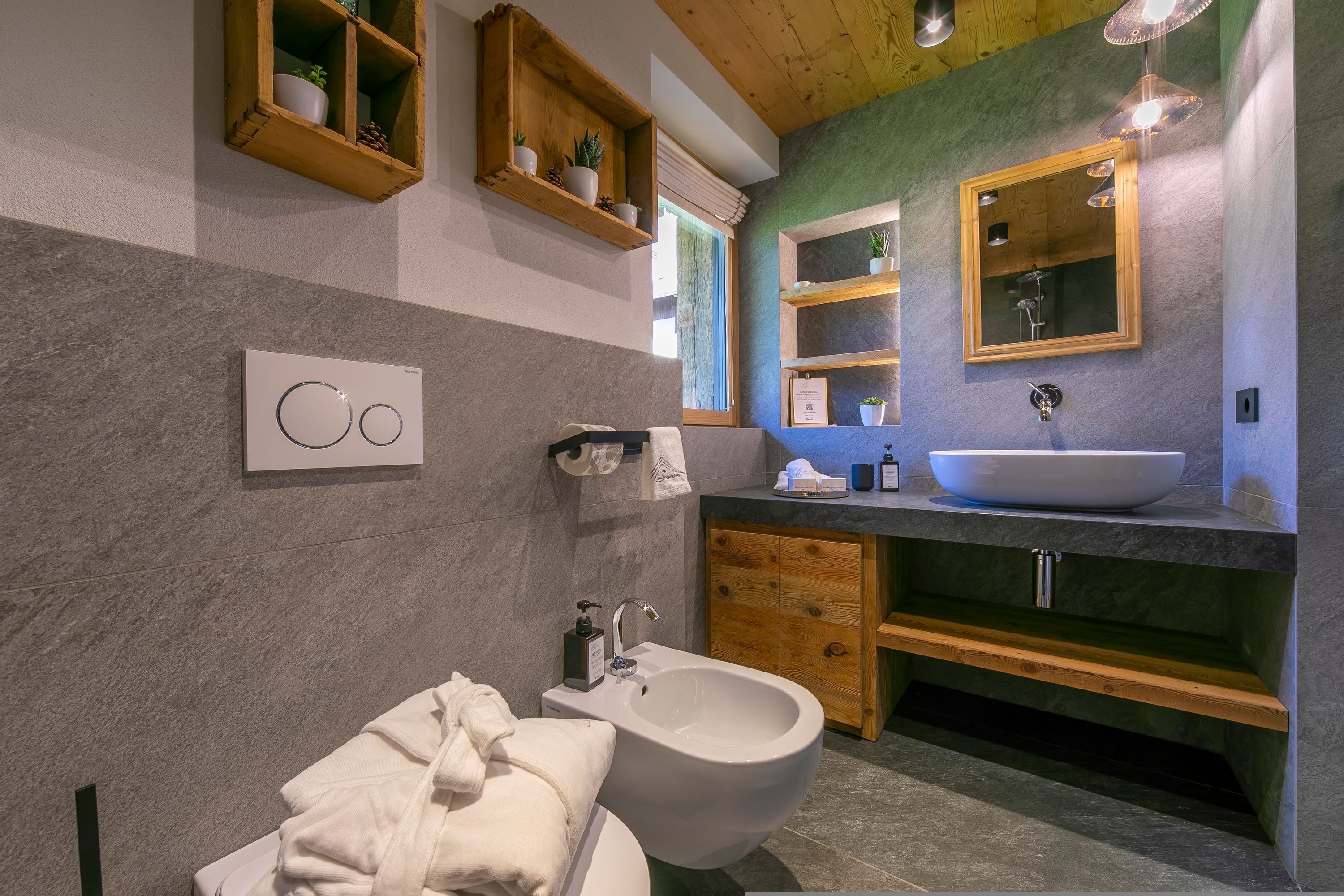 Une salle de bain moderne avec un bidet, des étagères en bois, un grand miroir et un mur en marbre.