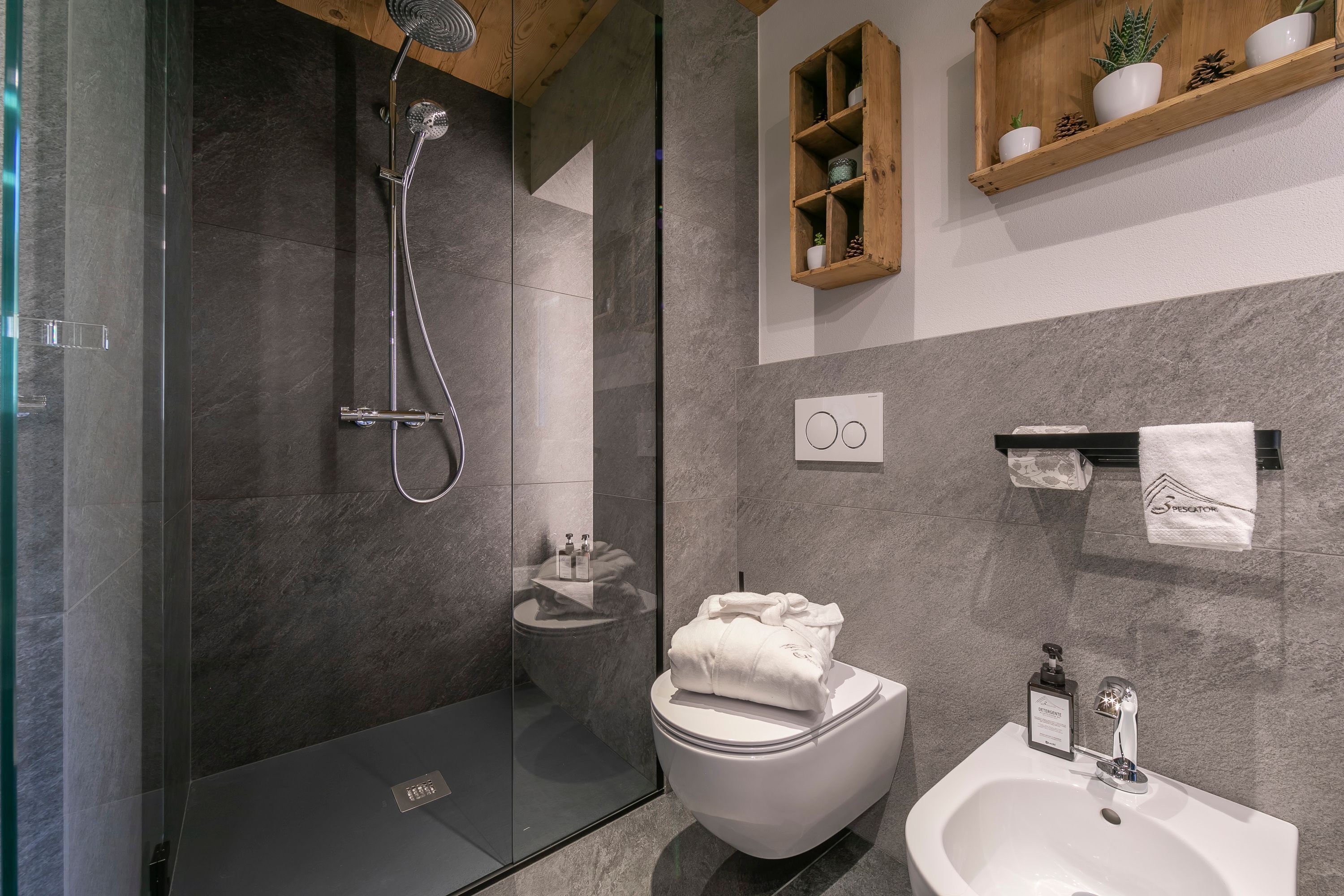 A modern bathroom with a glass-enclosed shower, a toilet, and a sink.