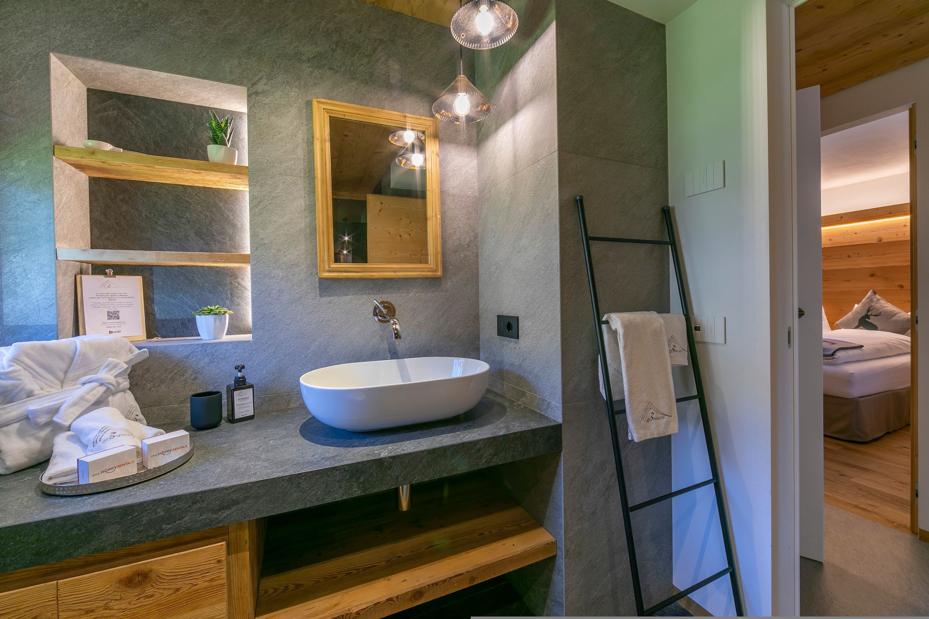 A modern bathroom with a large mirror, a vessel sink, wooden shelves, and a ladder.