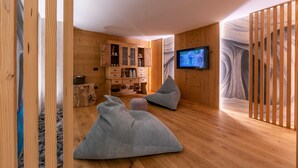 A modern interior with wooden walls, a television, a sofa, and a cabinet. - Giulia in Livigno With 2 Bedrooms and 2 Bathrooms (Livigno)