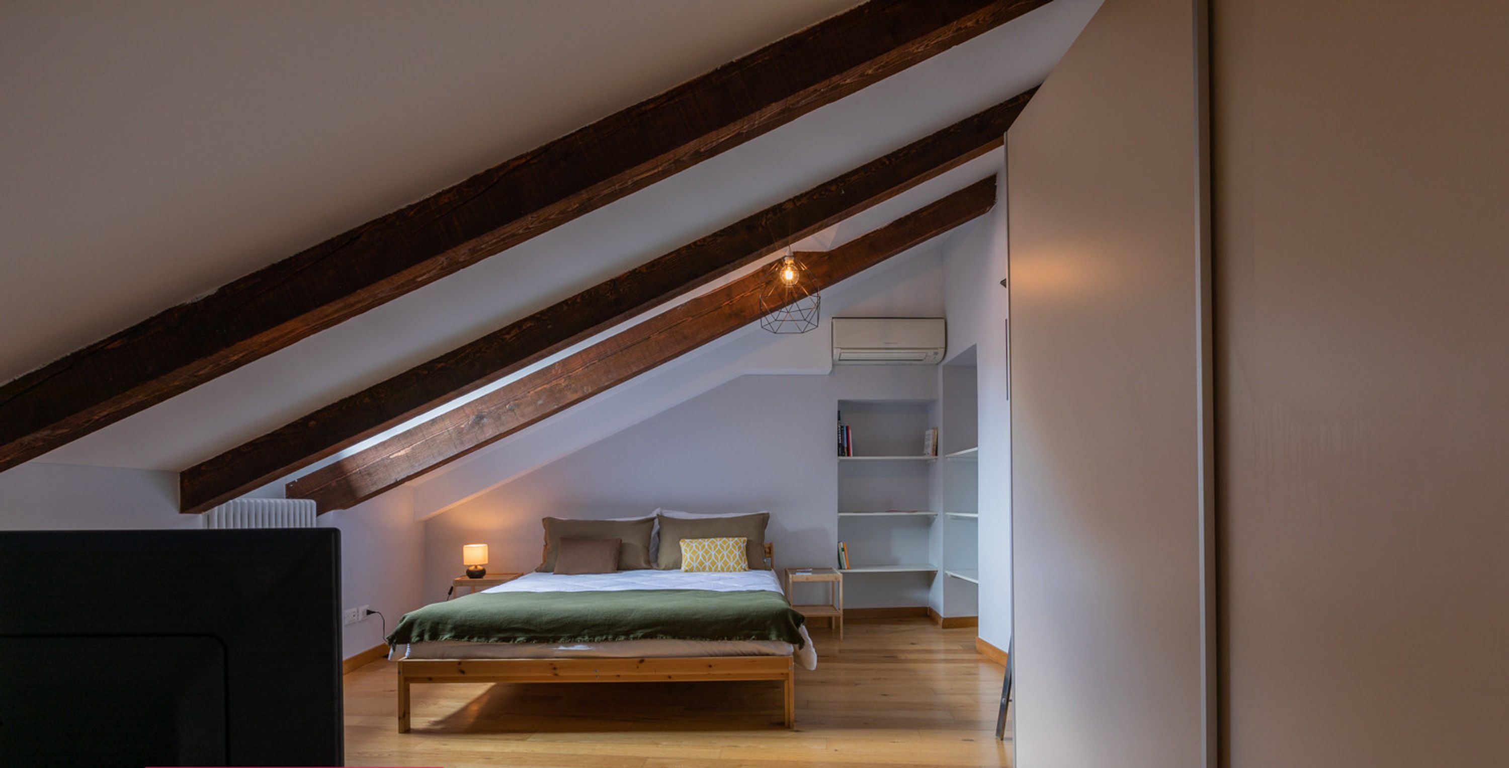 Ein Schlafzimmer mit Schlafbox, Holzbalken, Fernseher und Nachttisch.