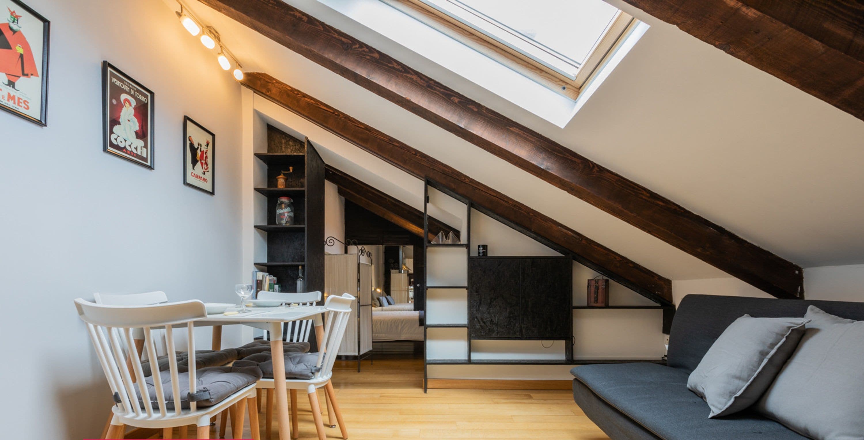 A modern loft apartment with a dining area, a sofa, and a skylight.