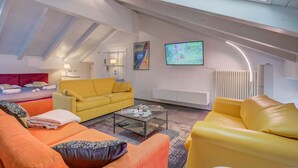 Ein moderner Loft-Wohnbereich mit hohen Decken, einem Oberlicht und einem großen Flachbildfernseher an der Wand.