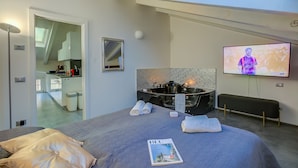 Ein modernes Hotelzimmer mit einem großen Bett, einem Fernseher, einer Badewanne und einem Oberlicht.
