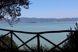 A view of a lake with a wooden railing in the foreground. - Thyme apt With Shared Pool (Castiglione del Lago)