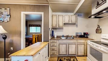 Une cuisine avec des meubles de rangement en bois, une cuisinière et un plan de travail.